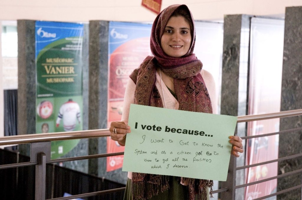 A woman holding a sign that says 'I vote because'